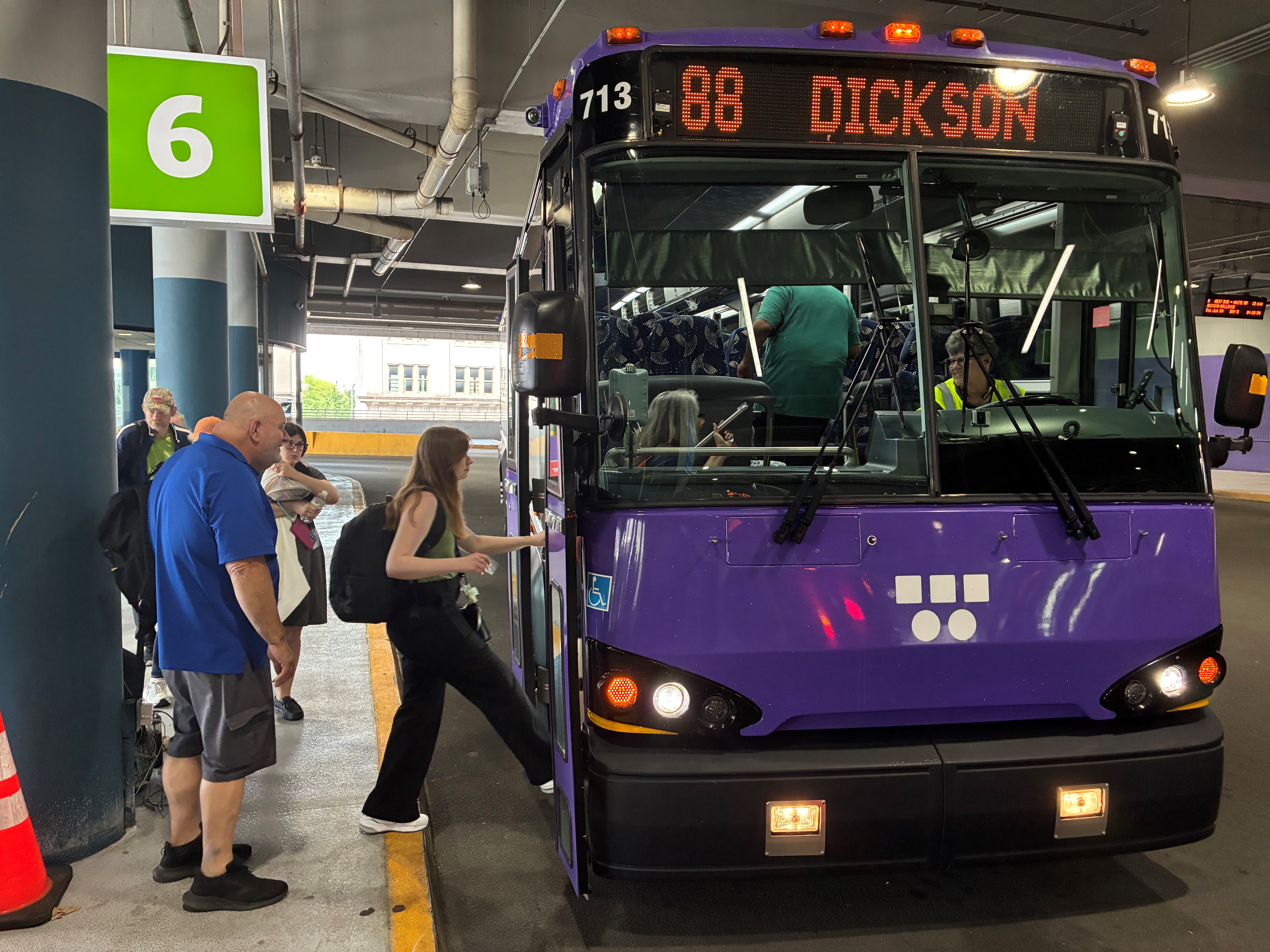 A purple WeGo bus marked 88 Dickson at station platform 6, with people boarding. The scene conveys a busy, routine, and organized transit environment.