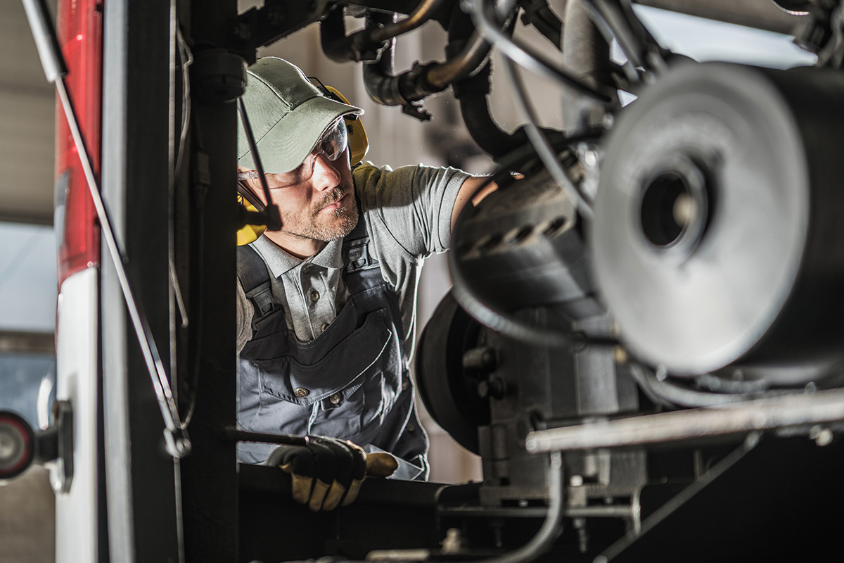 Automotive mechanic performing scheduled diesel engine service
